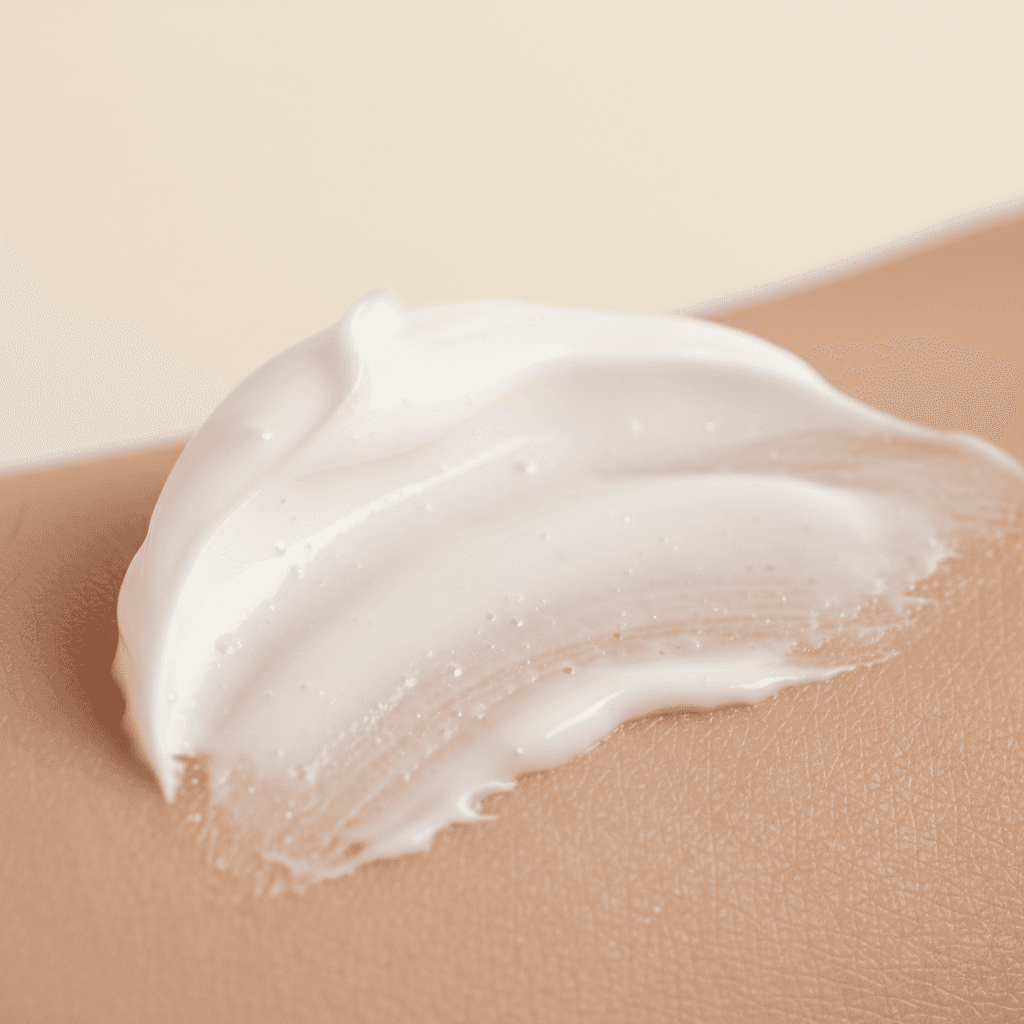 A restrained editorial macro of skincare cream texture across warm skin, framed to feel ingredient-led and non-clinical.