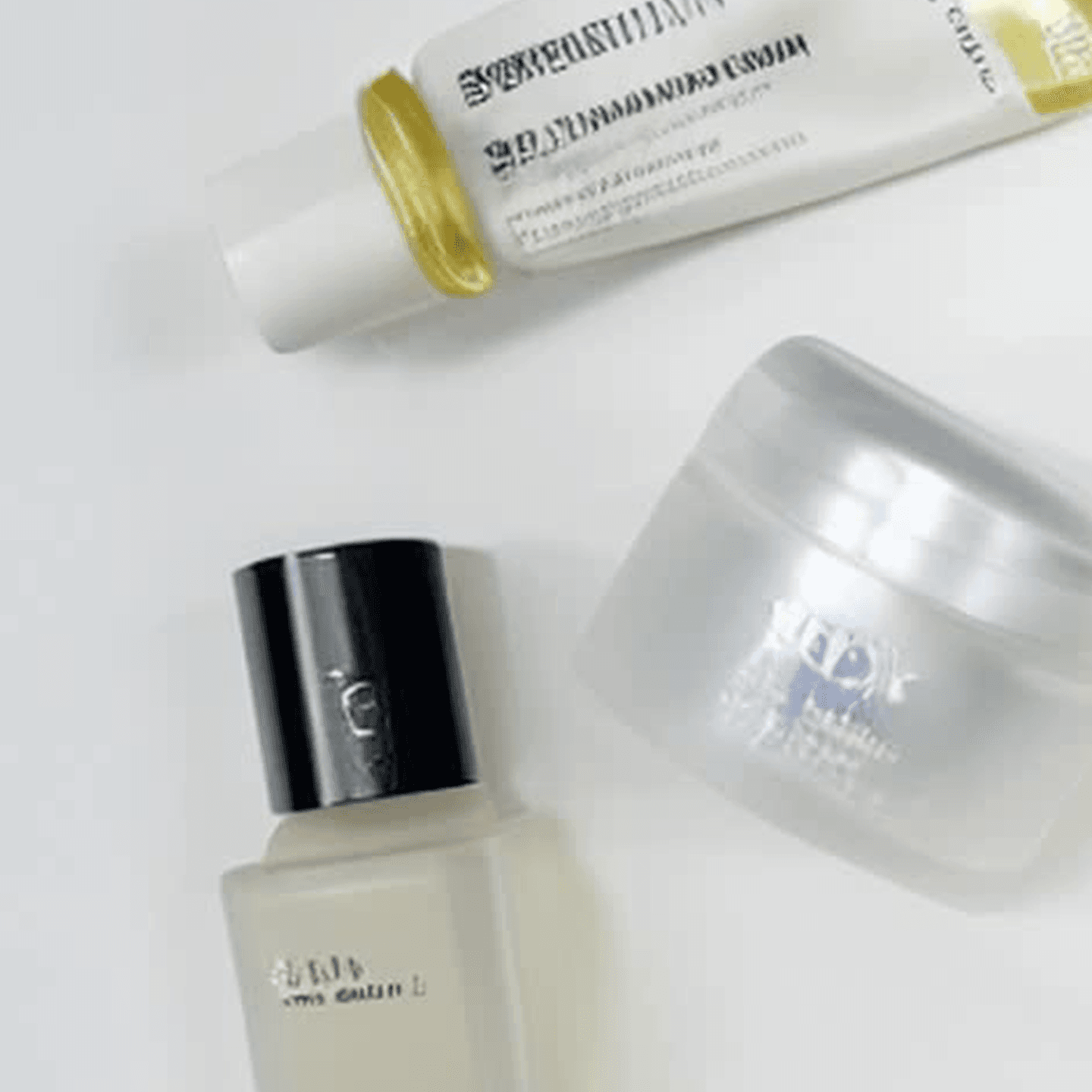 A restrained beauty flat lay showing skincare bottles and jars on a bright editorial surface.